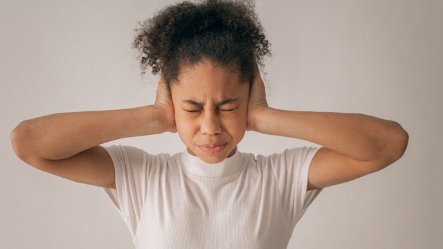 Stressed woman covering her ears with hands, expressing overwhelm and tension